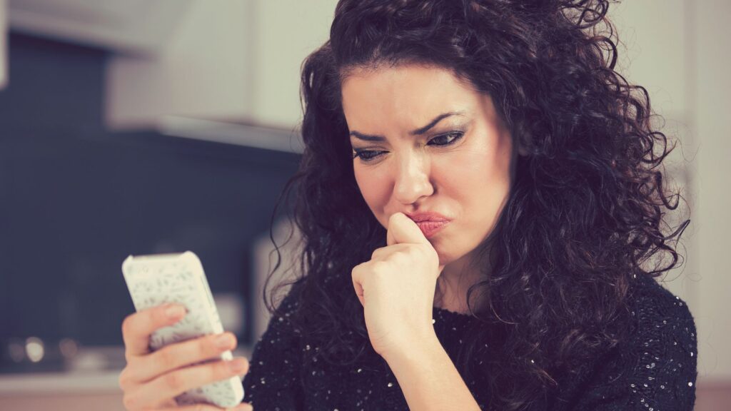 Woman looking at her phone in doubt