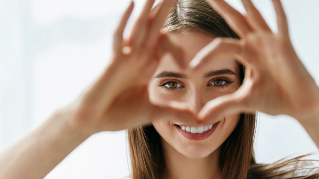 Woman making heart shape over her eyes