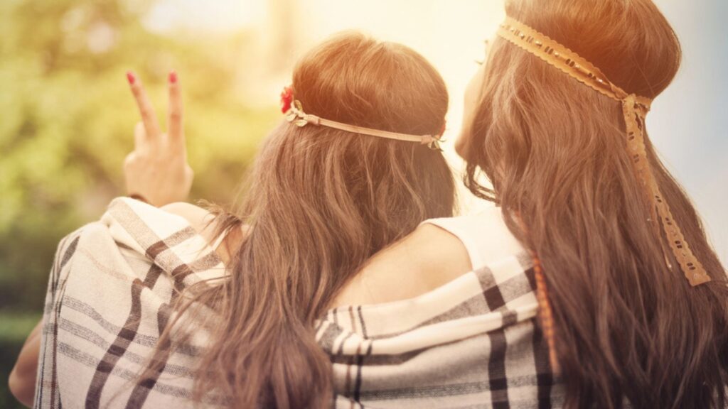 Boho female friends wrapped with blanket