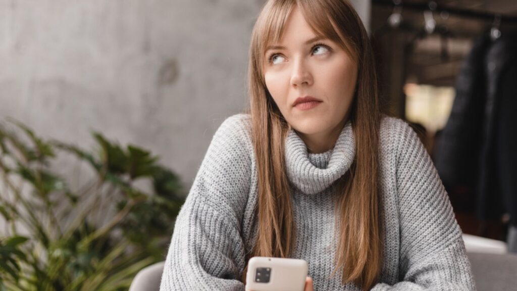 Woman looking at phone and rolling eyes